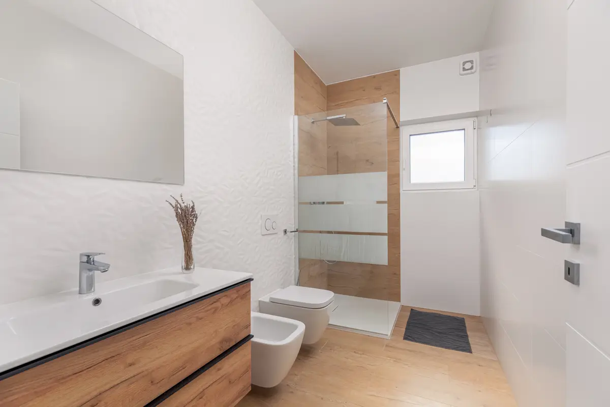 Fotografija brezhibno čiste in moderne kopalnice v apartmaju, ki gostom zagotavlja visoke standarde higiene in udobja ter je ključna za pridobivanje zaupanja in večje število rezervacij.