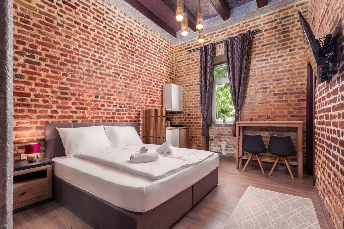 Fotografija, ki prikazuje edinstven karakter apartmaja z izpostavljeno opečno steno, potencialnim gostom obljublja avtentično in nepozabno bivanje, kar vodi do večjega števila rezervacij.
