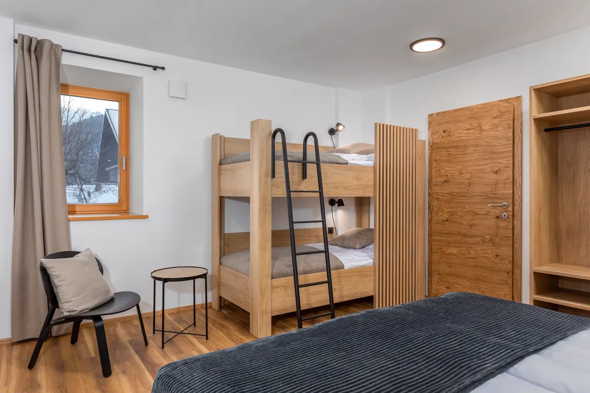 Profesionalna fotografija družinske sobe v apartmaju, ki s čistim dizajnom in pogradom jasno sporoča, da je nastanitev idealna za družine z otroki, kar povečuje zasedenost.