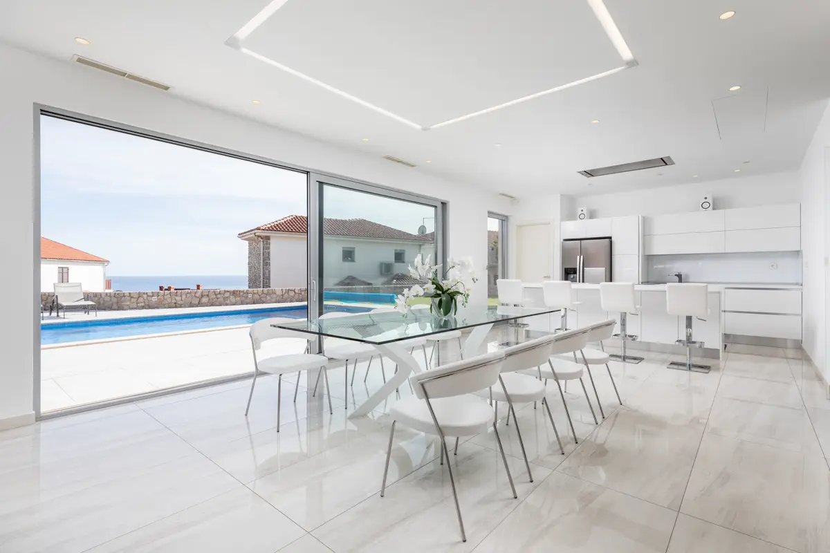 Profesionalna fotografija svetle, minimalistično zasnovane dnevne sobe v luksuzni vili, ki poudarja čiste linije, visokokakovostne materiale in sodoben prestiž, ključen za trg premium nepremičnin.