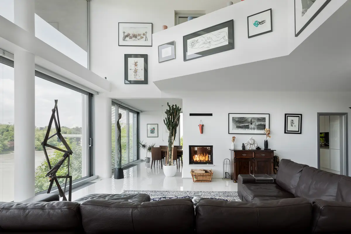 Fotografija, ki poudarja arhitekturno posebnost nepremičnine: impresivno dnevno sobo z galerijo, kaminom in odprtim pogledom, kar ustvarja občutek izjemne prostornosti in prestiža.