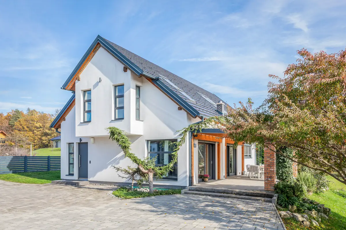 Fotografija zunanjosti moderne družinske hiše, ki s poudarkom na urejeni okolici in privlačni arhitekturi ustvari odličen prvi vtis in je ključna za vzbuditev zanimanja pri potencialnih kupcih.