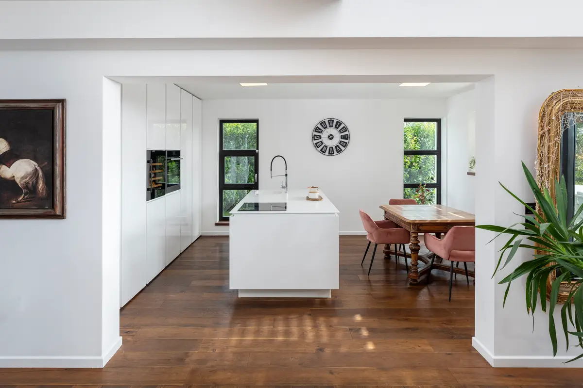 Fotografija prostorne, moderne kuhinje z otokom kot središčem dogajanja, ki učinkovito poudarja odprt tloris in je ključna za pritegnitev zanimanja kupcev, saj kuhinja prodaja hišo.