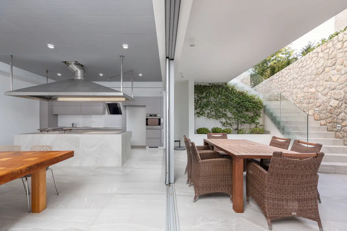 Fotografija, ki poudarja glavno prednost moderne hiše: popolno povezanost notranje kuhinje z zunanjo teraso, kar ustvarja idealen prostor za druženje in prodaja sodoben življenjski stil.