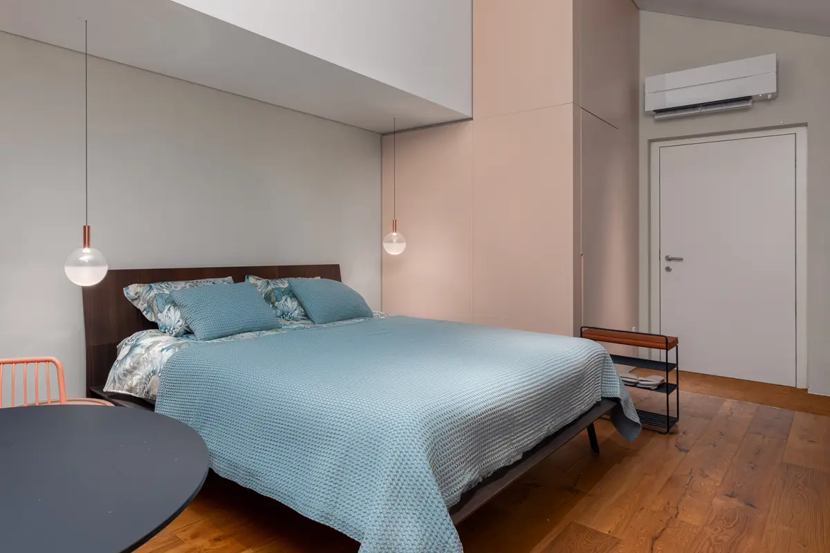 Fotografija prostorne spalnice v moderno opremljenem apartmaju, ki z minimalističnim dizajnom in umirjenimi barvami gostom obljublja sproščujoč in udoben oddih.