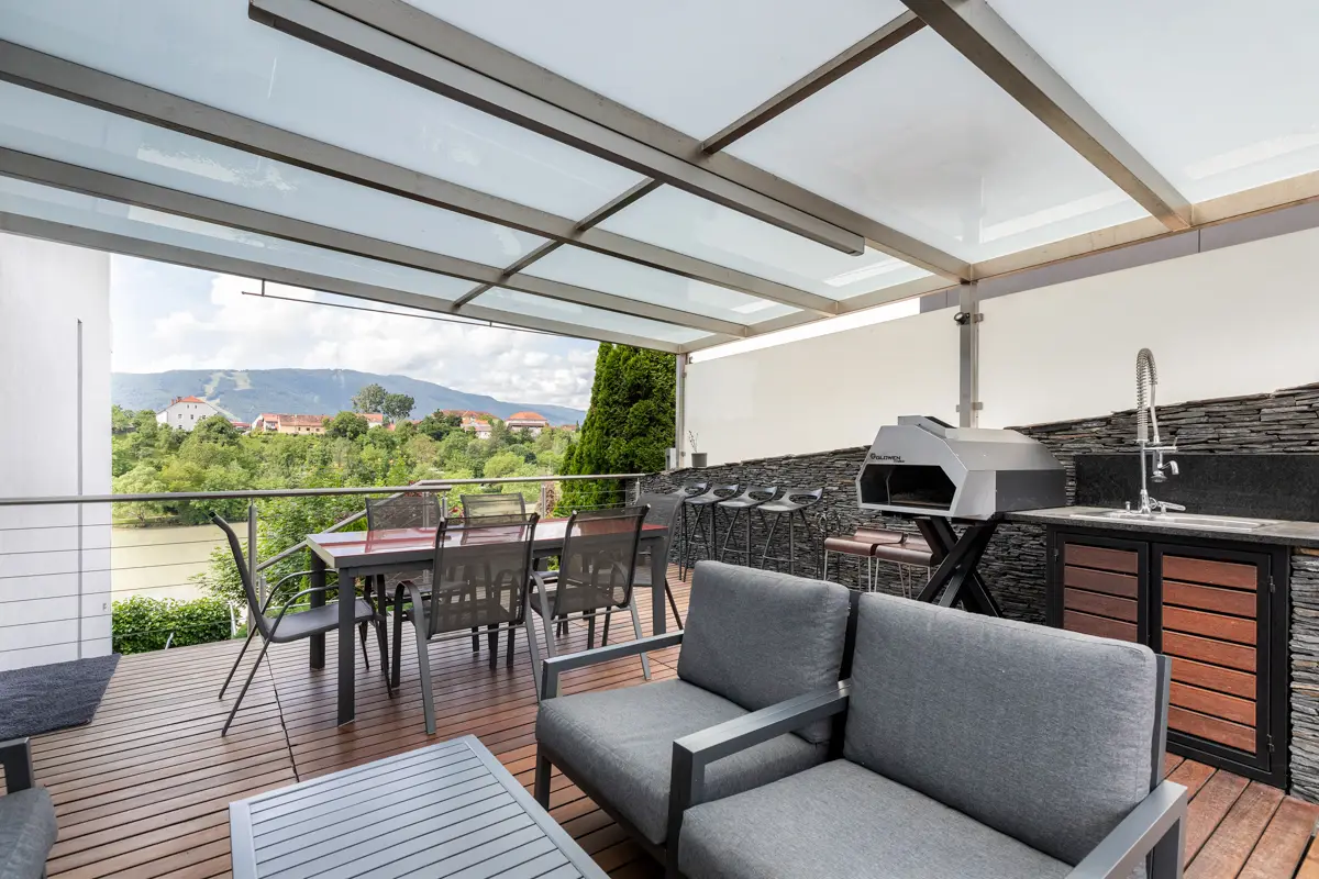 Fotografija prostorne, pokrite terase z moderno letno kuhinjo in jedilnico, ki poudarja življenjski stil in dodano vrednost nepremičnine za hitrejšo prodajo. 4