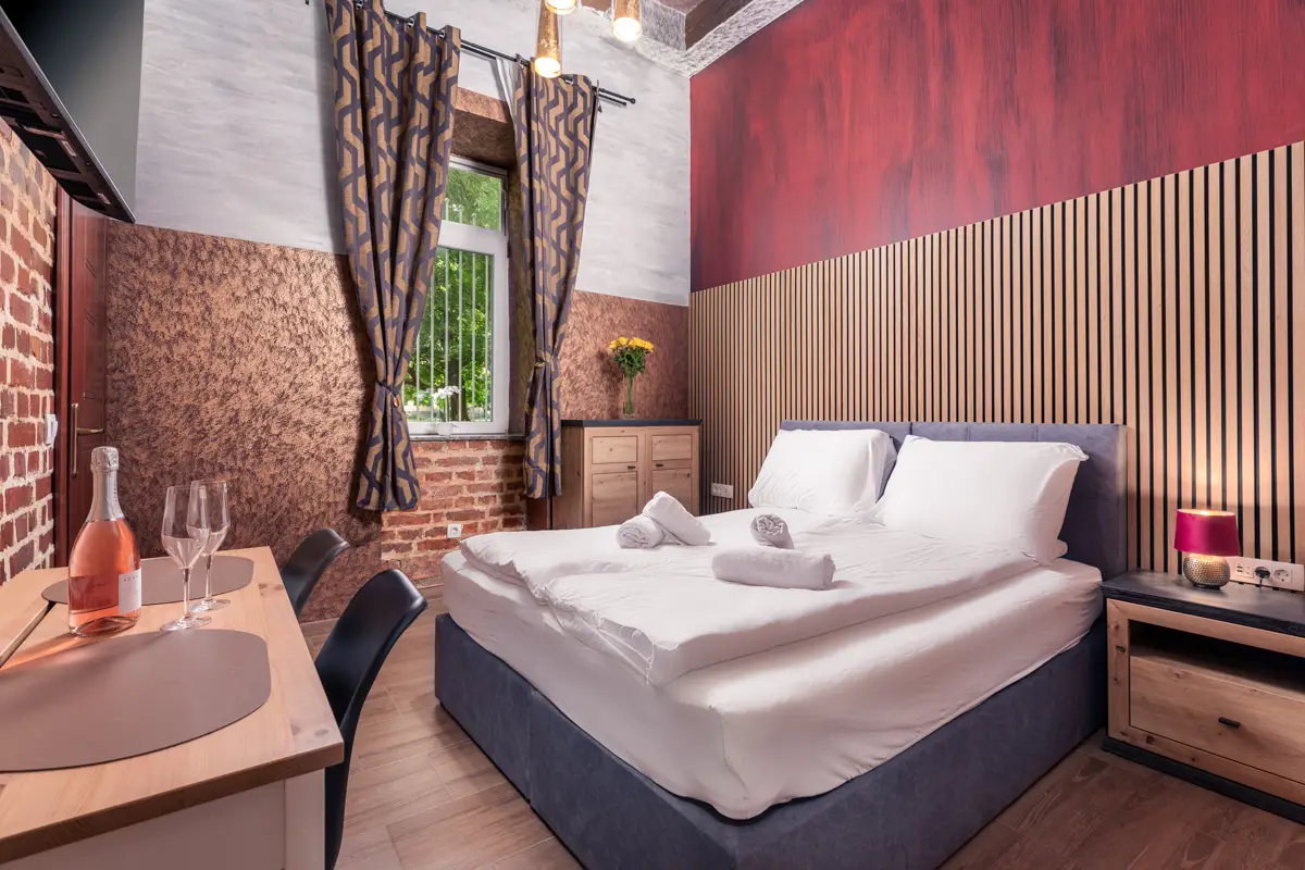 Fotografija butične sobe z unikatnim dizajnom, pripravljene za romantičen oddih. Poudarek na ambientu in posebnem doživetju pritegne goste, ki iščejo več kot le prenočišče.